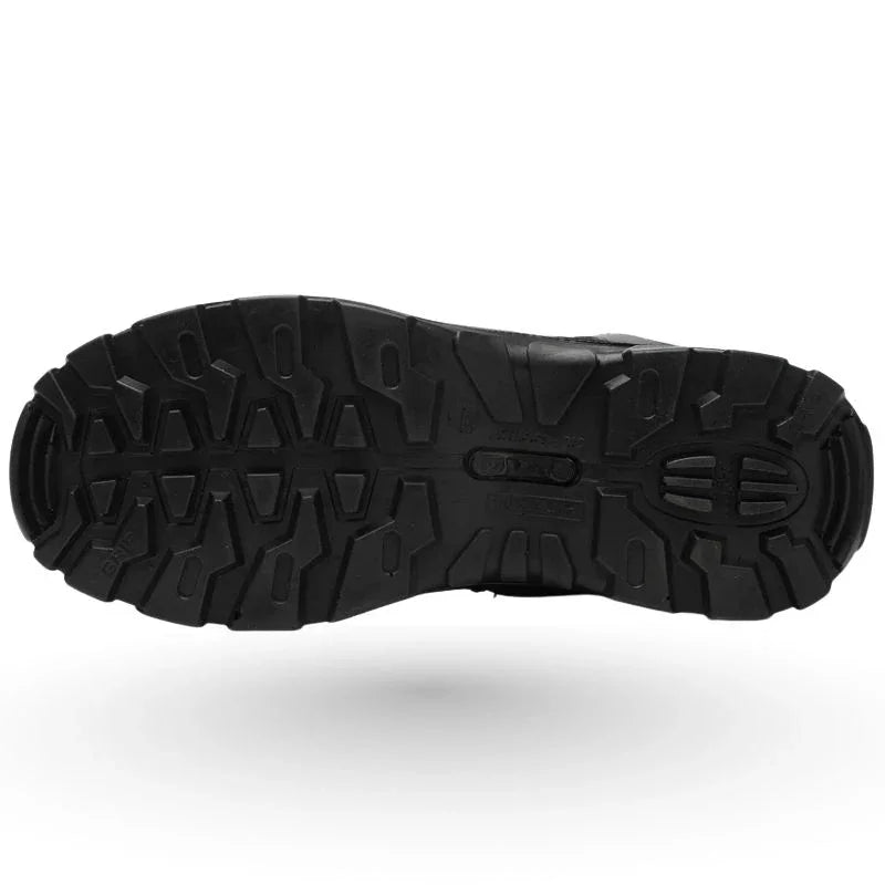 Vue de dessous d’une semelle crantée de rangers coquées noires, conçue pour une adhérence renforcée sur terrains glissants ou accidentés